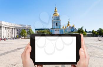 travel concept - tourist photographs St Michael's Square and Saint Michael's Golden-Domed Monastery in Kiev city in Ukraine on tablet with cut out screen for advertising logo