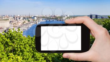 travel concept - tourist photographs Kiev city with River Port and Dnieper River from Volodymyrska Hill (Saint Volodymyr Hill) in Ukraine in spring on smartphone with cut out screen for advertising