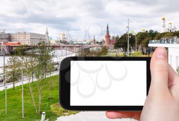 travel concept - tourist photographs Zaryadye park on Moskvoretskaya Embankment of Moskva River in Moscow city in autumn on smartphone with cut out screen for advertising logo