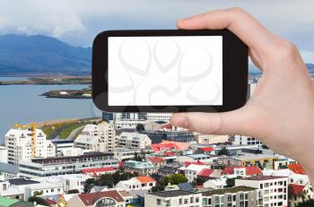 travel concept - tourist photographs Midborg district and Atlantic Ocean coast in Reykjavik city in Iceland in september on smartphone with cut out screen for advertising logo