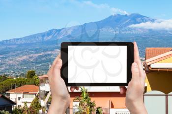 travel concept - tourist photographs residential houses in Giardini-Naxos town and Etna Mount in Sicily Italy in summer day on tablet with cut out screen for advertising logo