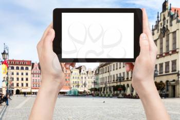 travel concept - tourist photographs central Market Square (Rynek) in Wroclaw city in Poland in autumn morning on tablet with cut out screen for advertising logo