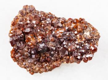 macro shooting of natural mineral rock specimen - rough Andradite garnet crystals on stone on white marble background from Primorsky Krai, Russia