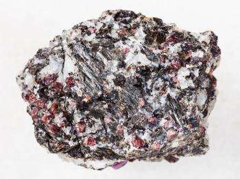 macro shooting of natural mineral rock specimen - rough gneiss stone with corundum crystals on white marble background from Hit-island of Upper Pulongskoye Lake, Karelia in Russia