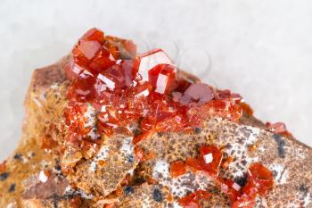 macro shooting of natural mineral rock specimen - raw crystals of Vanadinite stone close up on white marble background from Morocco