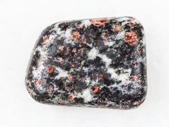 macro shooting of natural mineral rock specimen - red Garnet crystals in polished Hornblende stone on white marble background from Nigrozero region of Karelia, Russia