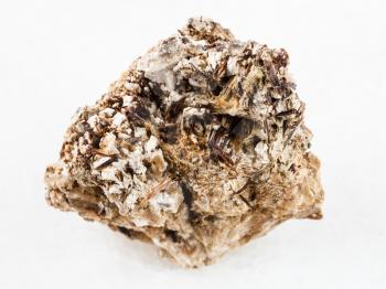 macro shooting of natural mineral rock specimen - brown Astrophyllite crystals in rough Natrolite stone on white marble background from Khibiny Mountains, Kola Peninsula, Russia