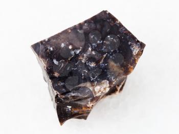 macro shooting of natural mineral rock specimen - raw black Flint stone on white marble background