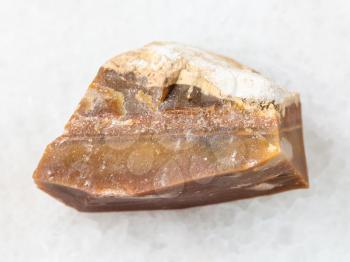 macro shooting of natural mineral rock specimen - rough brown Flint stone on white marble background