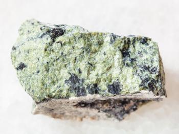 macro shooting of natural mineral rock specimen - rough serpentinite stone on white marble background