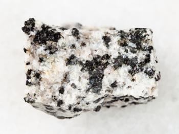 macro shooting of natural mineral rock specimen - rough white granite stone on white marble background