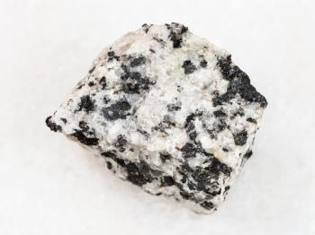 macro shooting of natural mineral rock specimen - raw white granite stone on white marble background