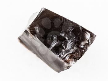 macro shooting of natural mineral rock specimen - piece of raw Obsidian (volcanic glass) stone on white marble background