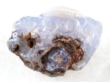 macro shooting of natural mineral rock specimen - rough crystal of blue Chalcedony gemstone on white marble background from Transbaikalia (Zabaykalye), Russia