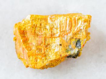 macro shooting of natural mineral rock specimen - rough native orpiment stone on white marble background from Yakutia, Russia