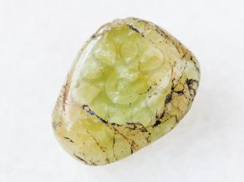 macro shooting of natural mineral rock specimen - tumbled green beryl gem stone on white marble background