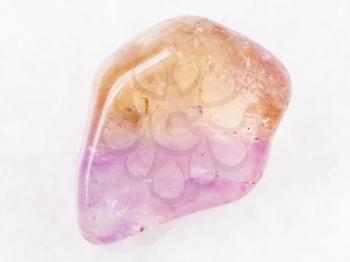 macro shooting of natural mineral rock specimen - tumbled Ametrine gemstone on white marble background from Brazil