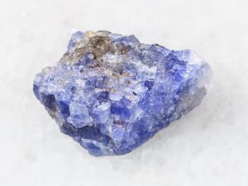 macro shooting of natural mineral rock specimen - rough crystal of Tanzanite gemstone on white marble background from Tanzania
