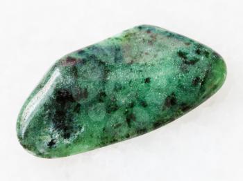 macro shooting of natural mineral rock specimen - polished zoisite gemstone on white marble background