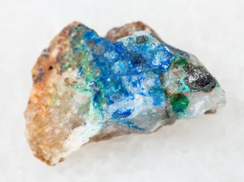 macro shooting of natural mineral rock specimen - tennantite crystal, green Tyrolite and blue Azurite on raw quartz stone on white marble background from Ural Mountains, Russia