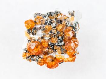 macro shooting of natural mineral rock specimen - rough crystals of spessartine garnet gemstone on white marble background from Fujian region, China