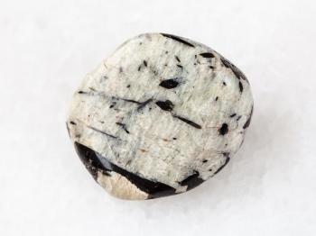 macro shooting of natural mineral rock specimen - black aegirine crystals in microcline gemstone on white marble background from Lovozero Massif, Kola peninsula, Russia
