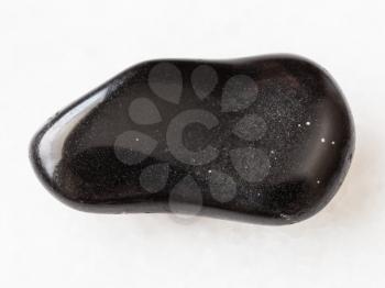 macro shooting of natural mineral rock specimen - polished black obsidian gemstone on white marble background from Mexico