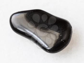 macro shooting of natural mineral rock specimen - black obsidian gemstone on white marble background from Mexico