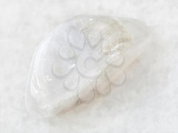 macro shooting of natural mineral rock specimen - polished white moonstone (adularia) gemstone on white marble background