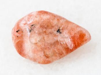 macro shooting of natural mineral rock specimen - polished sunstone (heliolite) gemstone on white marble background from USA