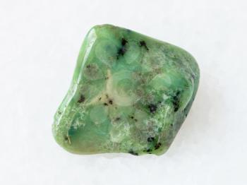 macro shooting of natural mineral rock specimen - polished green Grossular garnet gemstone on white marble background from South Africa