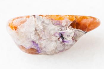 macro shooting of natural mineral rock specimen - charoite in tumbled Tinaksite gemstone on white marble background from Murun Massif, Yakutia, Russia