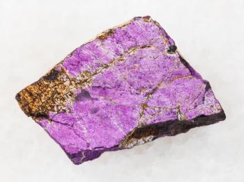 macro shooting of natural mineral rock specimen - raw Purpurite stone on white marble background from Karibib district, Namibia