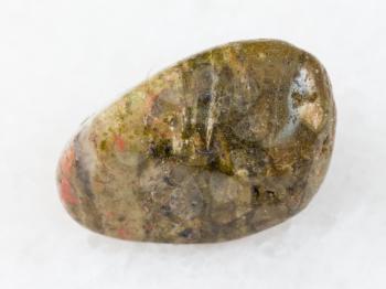 macro shooting of natural mineral rock specimen - polished unakite gem stone on white marble background from South Africa