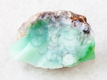 macro shooting of natural mineral rock specimen - rough crystal of Chrysoprase gemstone on white marble background from Kazakhstan
