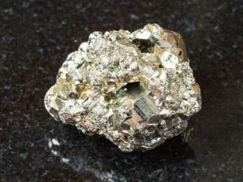 macro shooting of natural rock specimen - rough iron pyrite (fool's gold) stone on black granite background