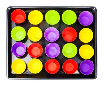 top view of tray with many empty multicolor silicone molds for cupcakes isolated on white background