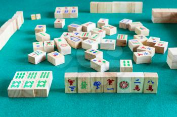 side view of gameboard of mahjong game, tile-based chinese strategy board game on green baize table