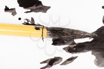 black painted round goat hair tip of bamboo paintbrush for sumi-e ( suibokuga) painting over ink blots on white paper close up