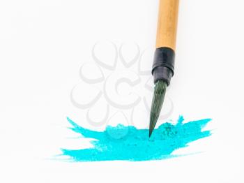 green colored tip of paintbrush for sumi-e ( suibokuga) painting in cyan blot on white paper close up