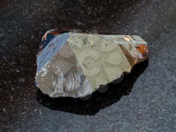 macro shooting of natural rock specimen - raw crystal of Cassiterite (Tin ore) stone on black granite background from Pravourmiyskoe deposit in Khabarovsk Krai, Russia