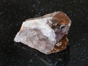 macro shooting of natural mineral - raw smoky quartz crystal on black granite from Ural Mountains