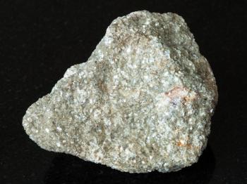 macro shooting of natural mineral - muscovite greisen rock with spessartine garnet crystal on black granite from Ural Mountains