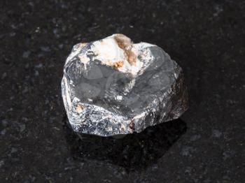 macro shooting of natural mineral - raw Hematite crystal on black granite from Central Ural Mountains