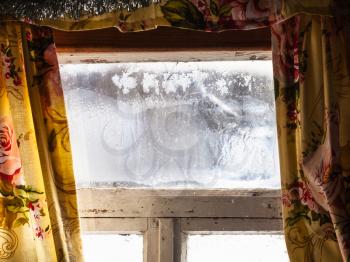 shabby frozen window in old russian rural house in cold winter day