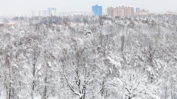 above view of snowy urban Timiryazevskiy park and residential district in Moscow city in winter evening