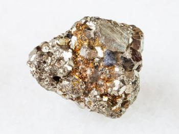 macro shooting of natural rock specimen - raw iron pyrite (fool's gold) stone on white marble background