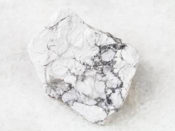 macro shooting of natural rock specimen - raw Howlite stone on white marble background