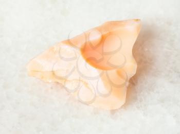 macro shooting of natural mineral - rough precious opal gemstone on white marble from Ural Mountains