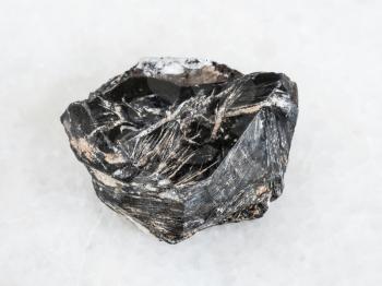 macro shooting of natural mineral - raw Hematite crystal on white marble from Central Ural Mountains